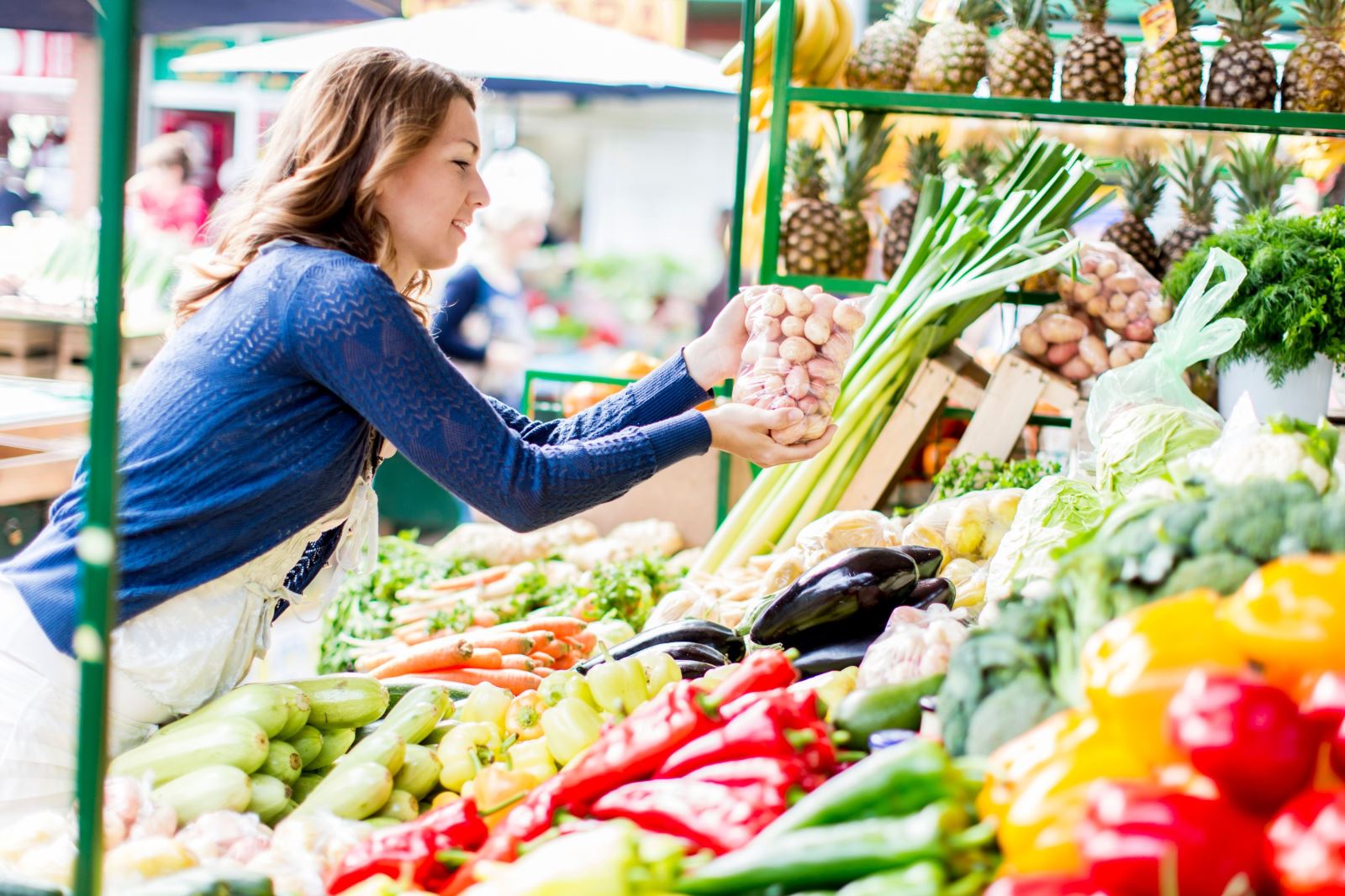 A lady leaning over a fruit and veg stall